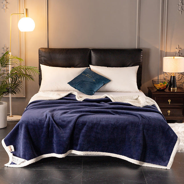 Ultra-soft double fleece blanket in navy blue on a bed with modern decor.