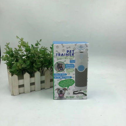 Dog Trainer Ultrasonic Handheld Bark-stop in packaging with potted plant background.